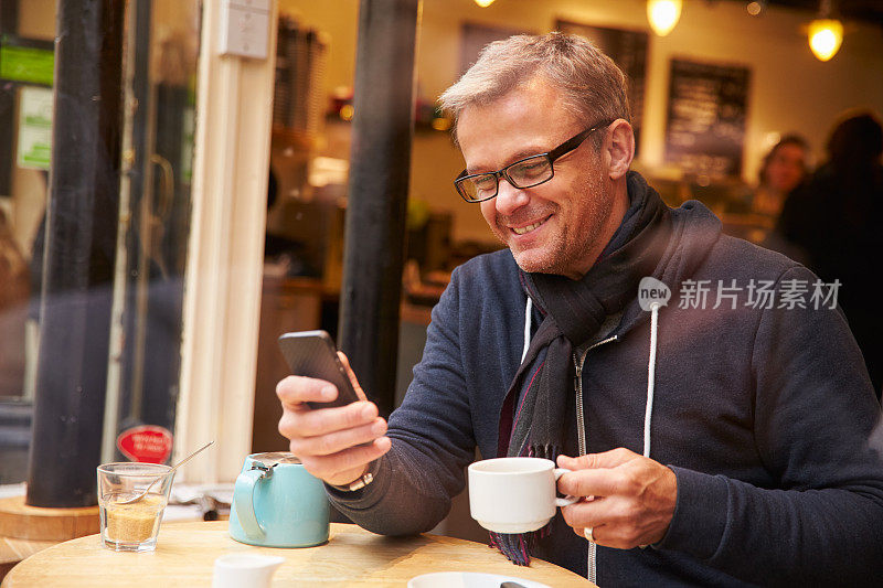 透过咖啡厅窗口看到的男人使用手机